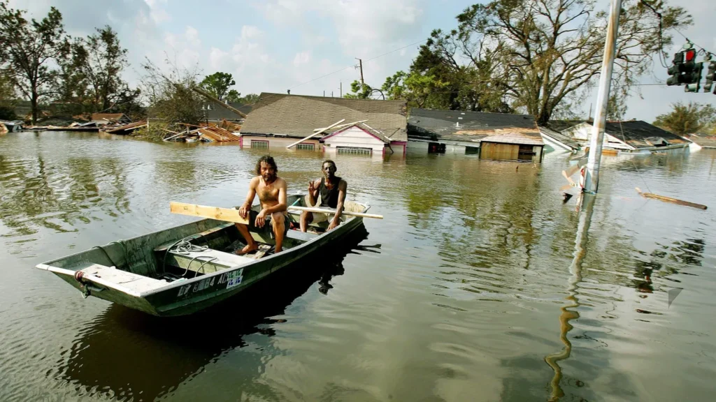 Two men paddle in high water in the Ninth Ward after Hurricane Katrina.